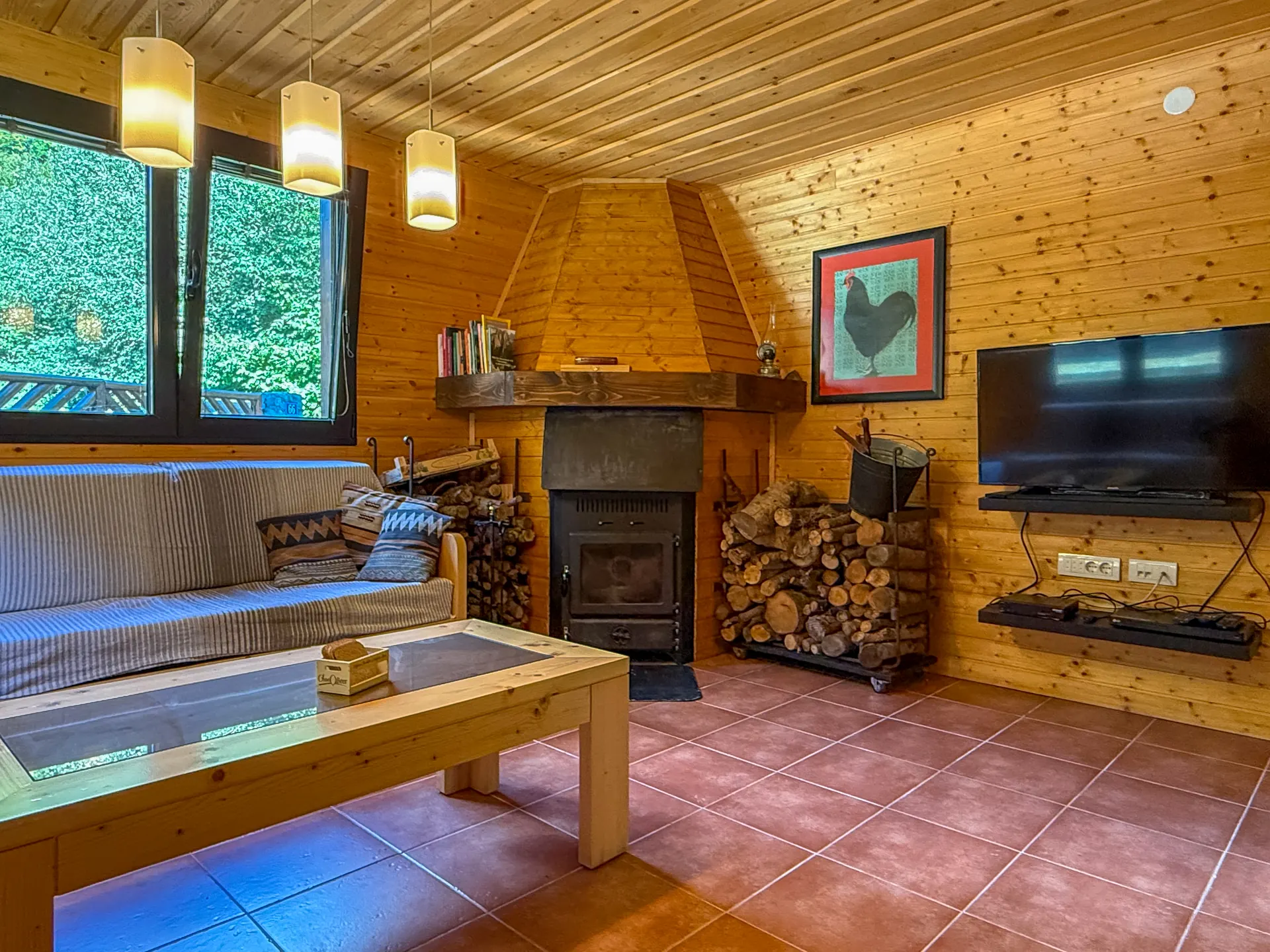 The wood-burning stove, a stack of logs and the sofa