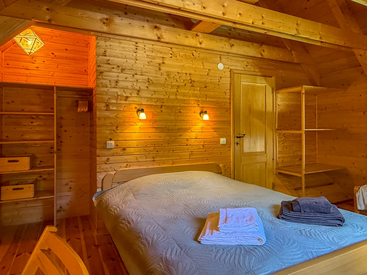 A bedroom with a double bed, wardrobe and warm wooden walls