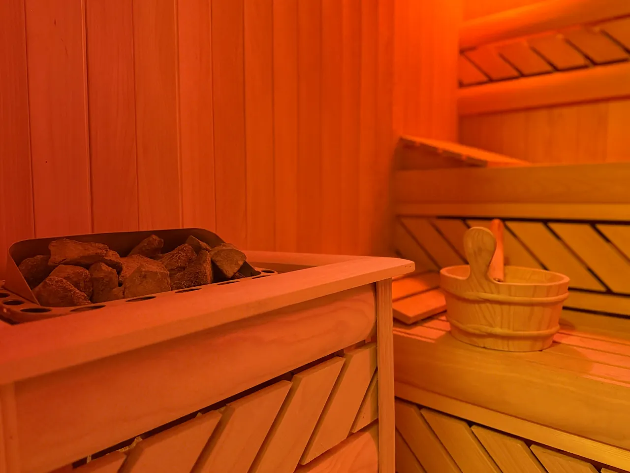 The sauna stove with stones and a wooden bucket