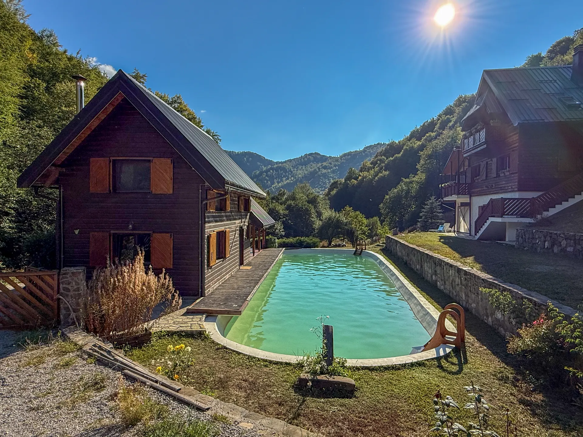 The pool and cabin in the sun, with the mountains beyond